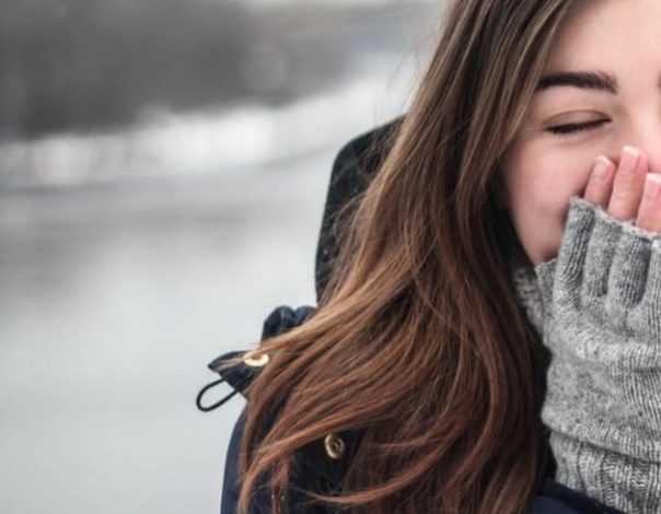 woman in winter clothes covering her face